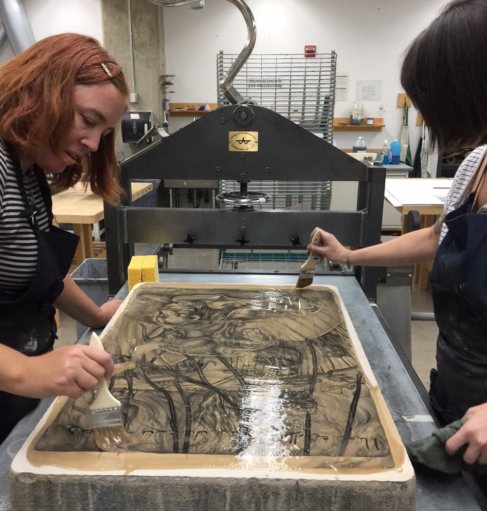 Two printers work on a lithographic stone designed by the artist