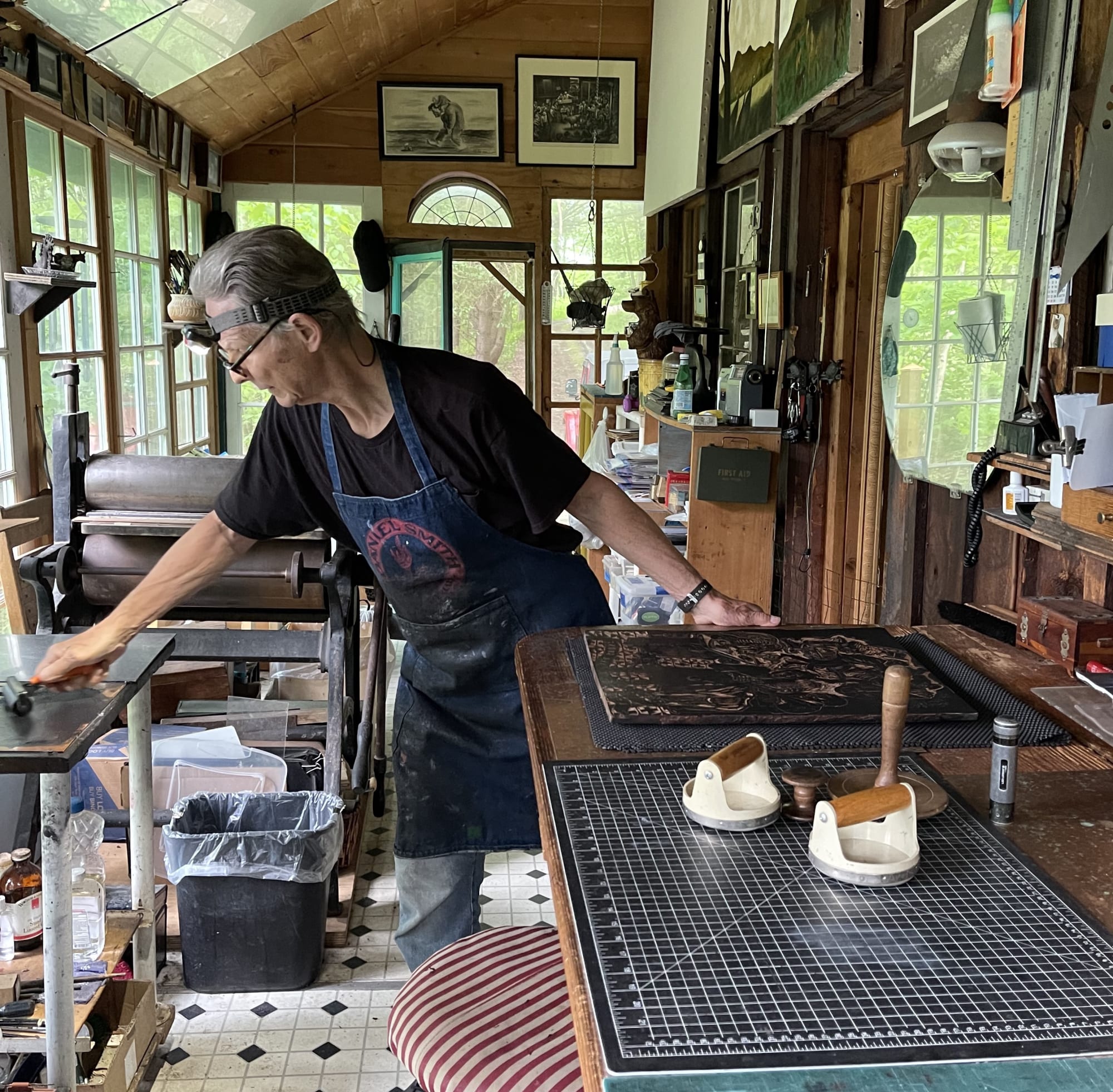 Photograph of printmaker Steve Murray inking the woodblock for a new Sue Coe print, The Martin Act, 2022