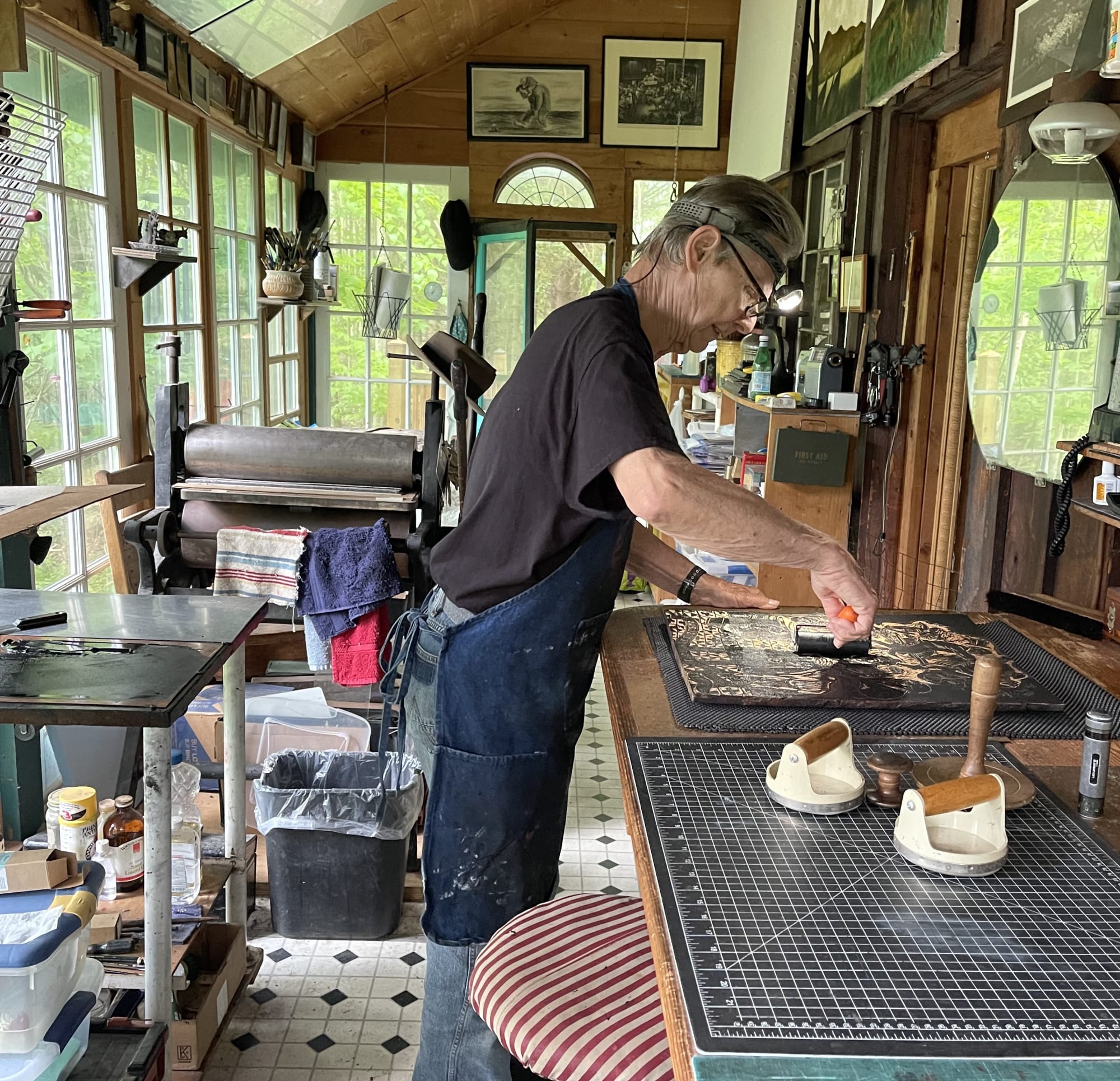 Photograph of printmaker Steve Murray inking the woodblock for a new Sue Coe print, The Martin Act, 2022