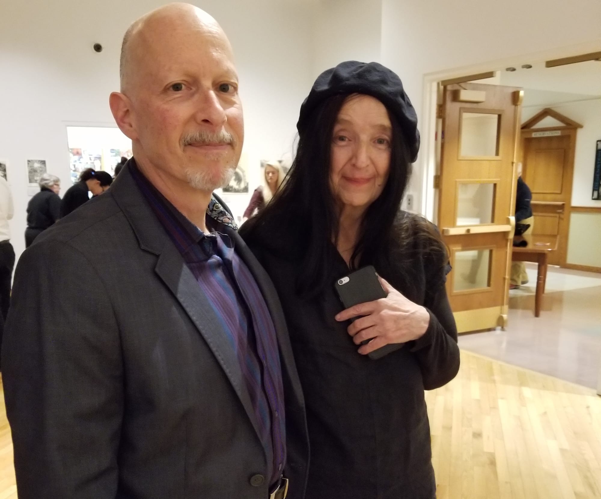 The artist Sue Coe stands with a man wearing a dark suit