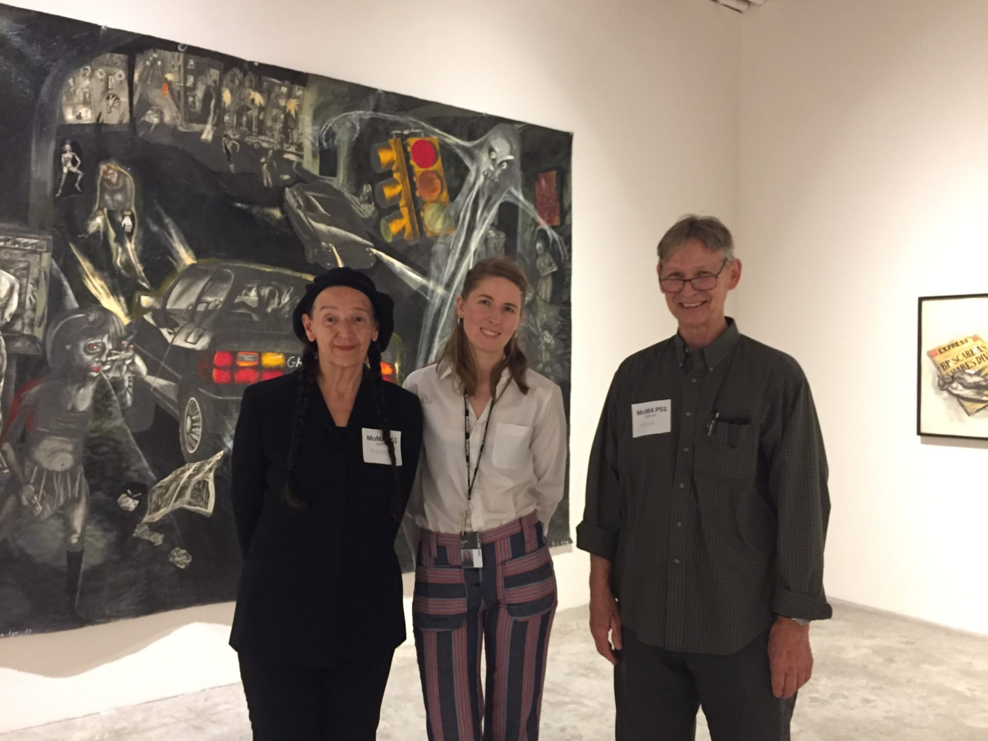 Photograph of Sue Coe, Josephine Graf and Steve Murray in front of large Coe painting at the opening of the one-woman Sue Coe exhibition "Graphic Resistance," MOMA PS1, Queens, NY 2018