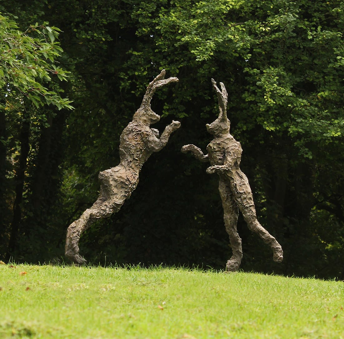 Bronze boxing hares in a garden setting