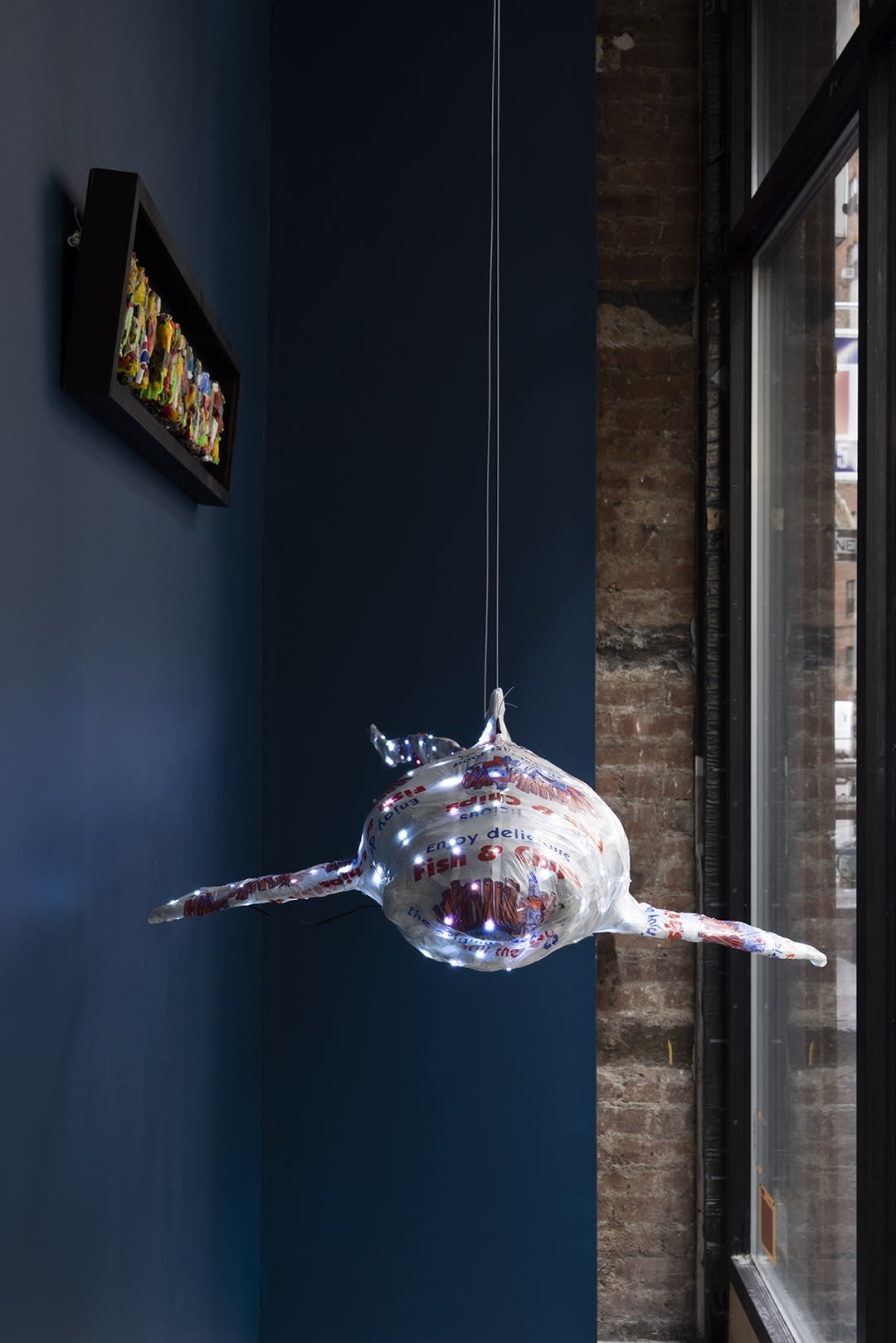 shark sculpture made from plastic bags hanging in windowfront