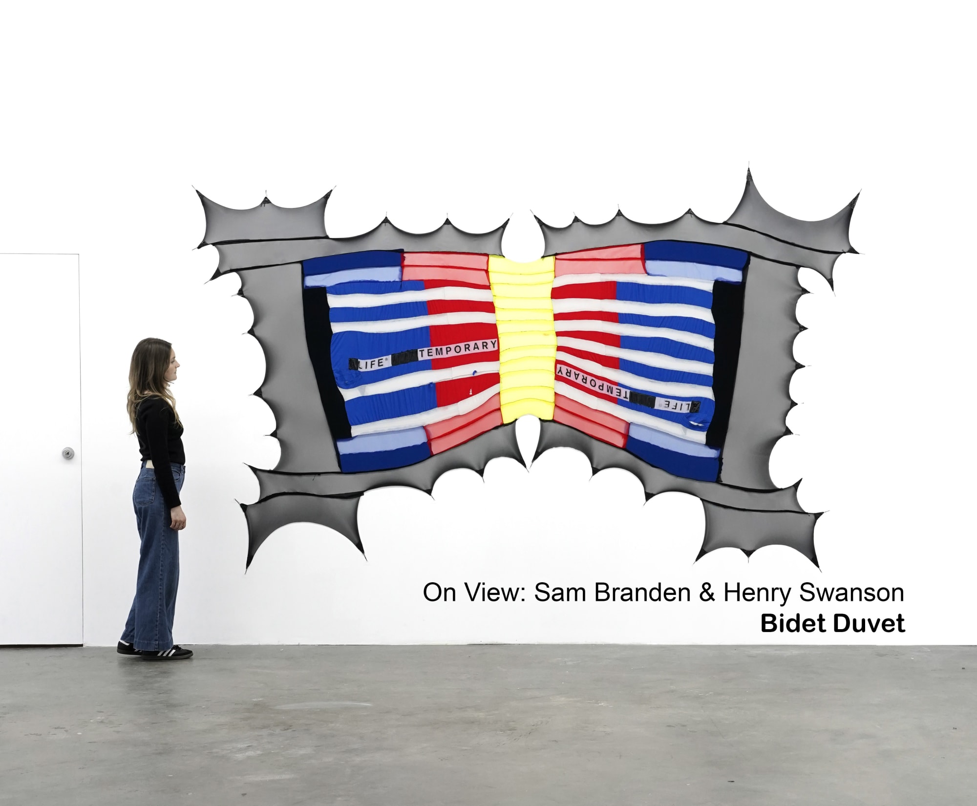 photo of a fabric artwor by Sam Branden stretched onto a wall with a woman standing next to it for scale