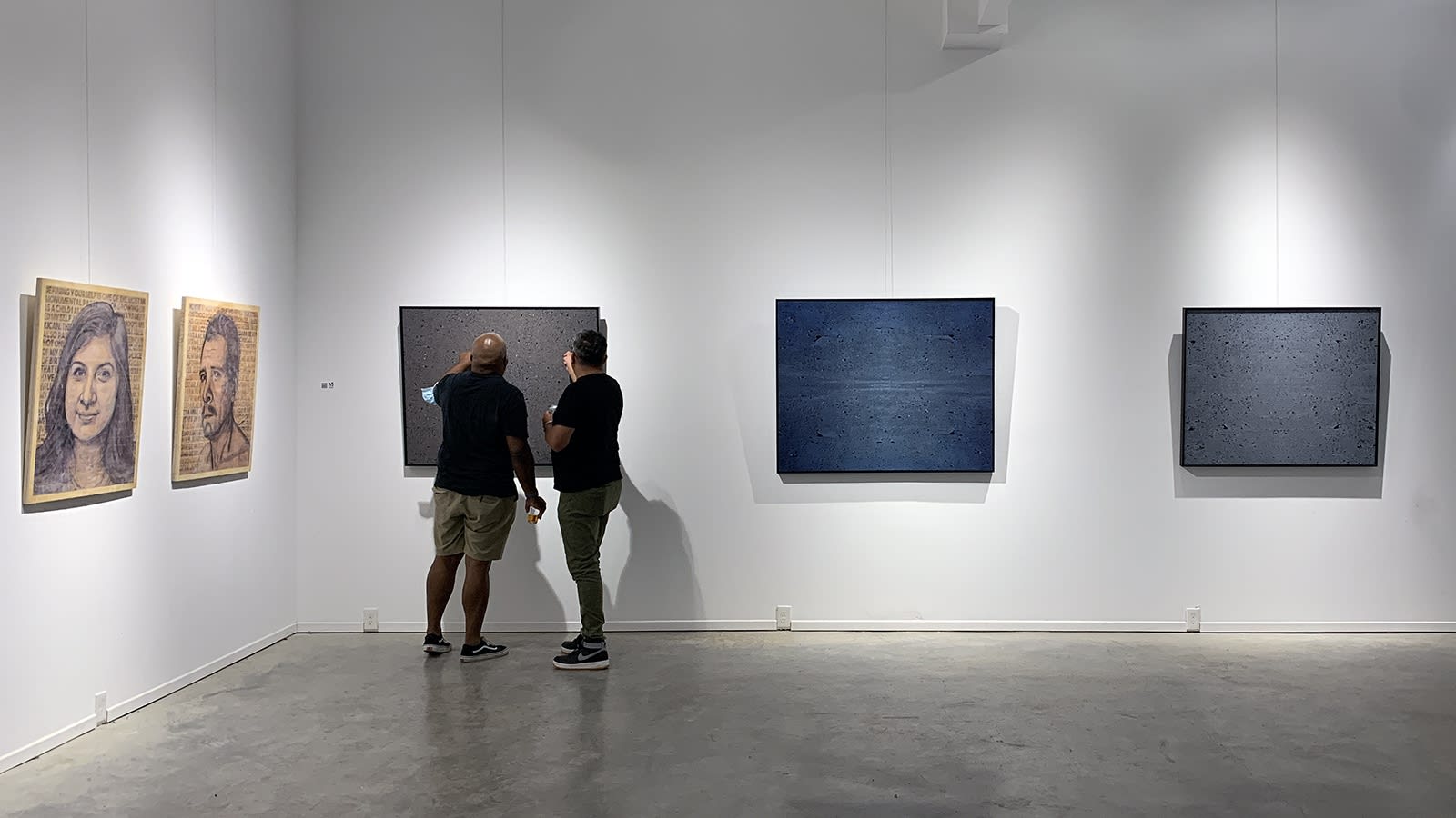 two people looking at paintings by Xie Caomin at the Waddi art gallery in Atlanta