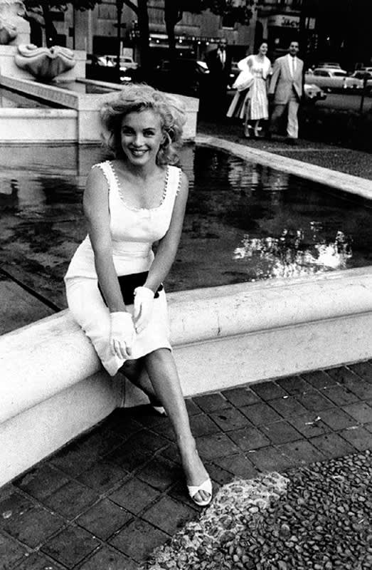 Black and white photograph of Marilyn Monroe sitting on a fountain