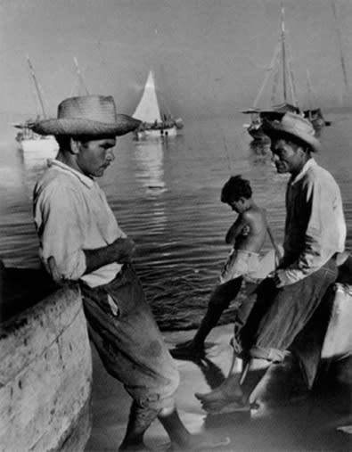 Black and white photograph of two men and a child on a port dock