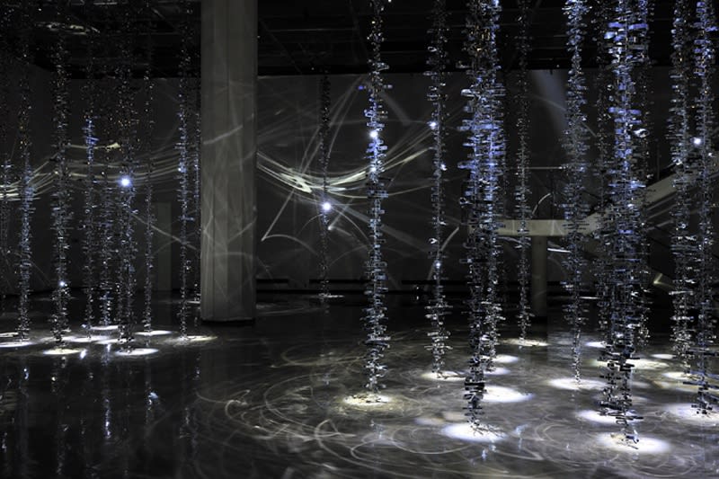 photograph of dangling lights and mylar in a dark art exhibition space