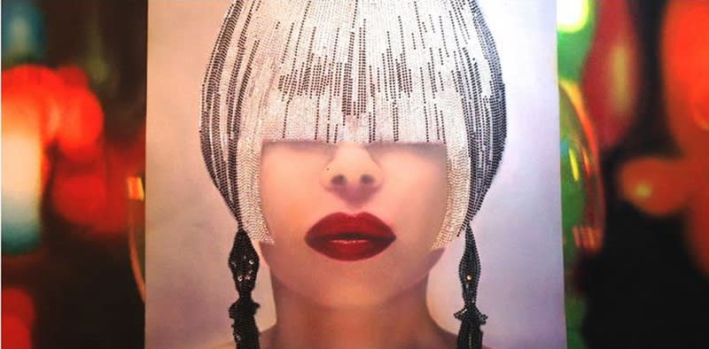 Painting of a female face obscured by bangs formed by small crystals