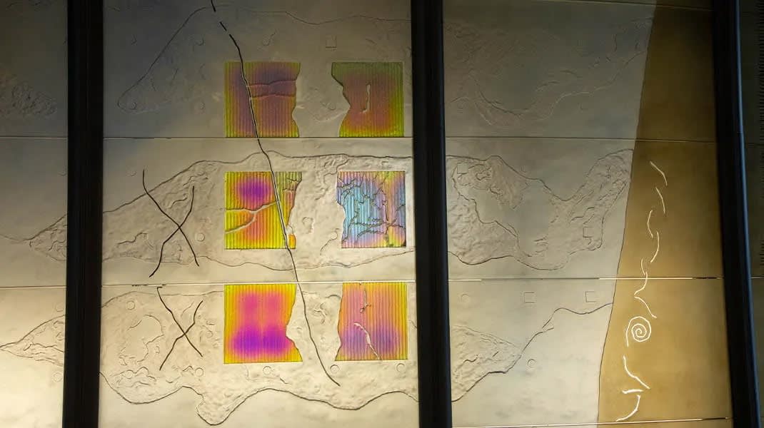 Detail of a large dichroic glass sculpture like an oversize modular screen (green, yellow, blue) 