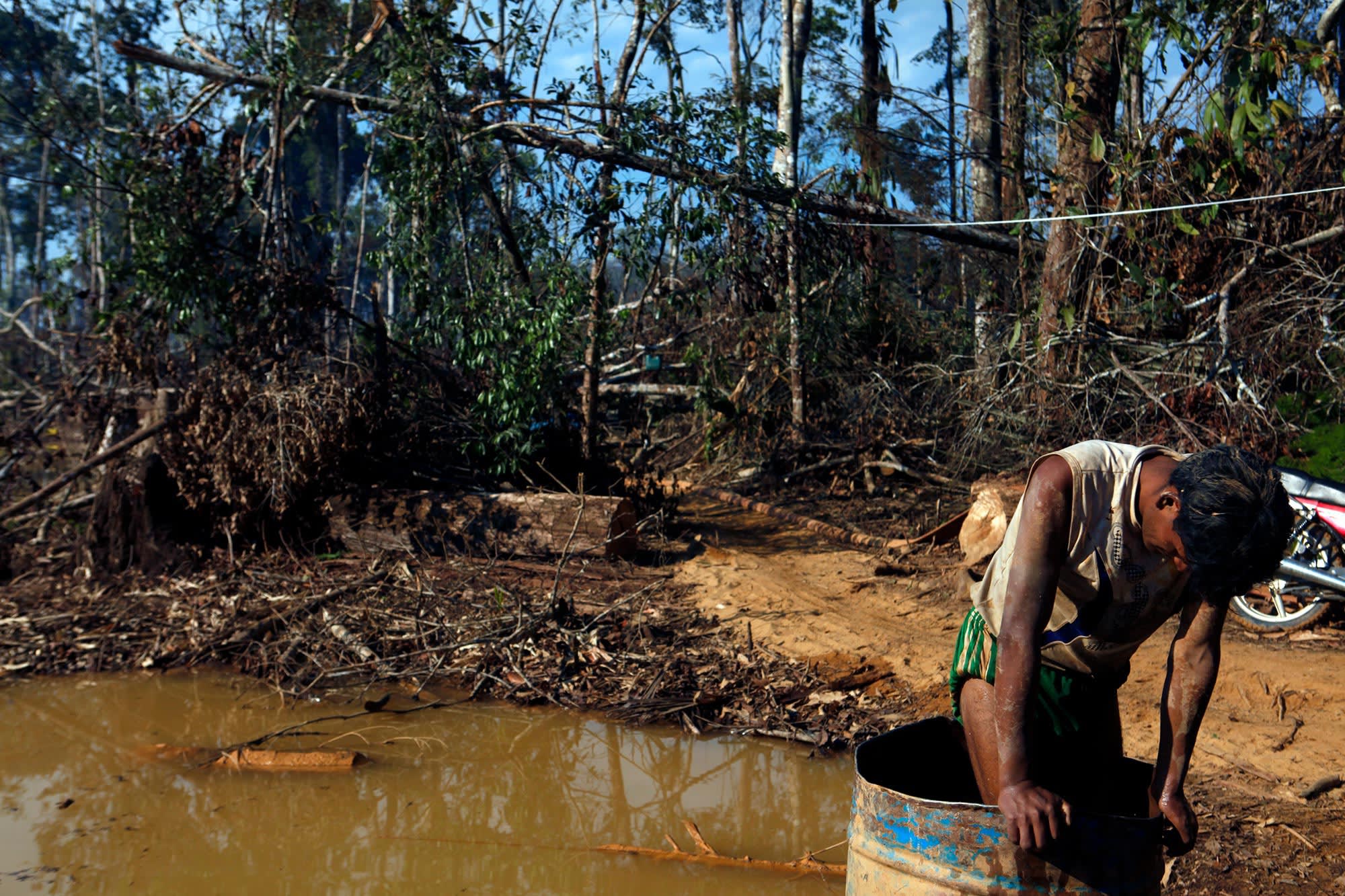 A gold miner stands in a barrel filled with mercury in order to separate the gold from the excavation matter, in the mining area of Lamal, Madre de Dios region, Peru