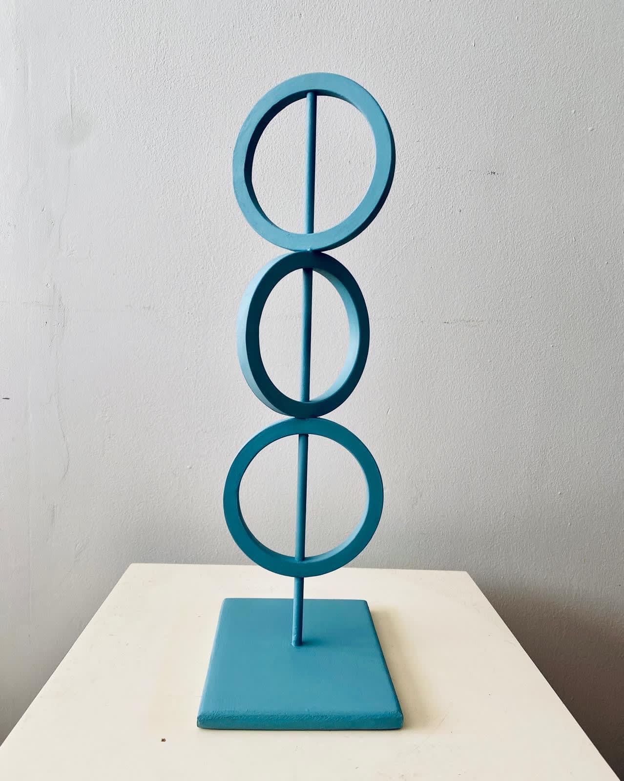 blue steel sculpture with three rings on top of each other representing Mind Body and Spirit.