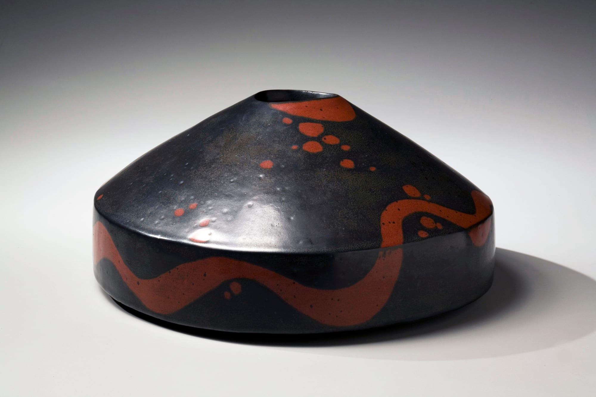 Flattened, round vessel with conical top and black and red iron-glazed design 2007 Glazed stoneware 6 1/4 x 13 x 12 in. Inv# 5350