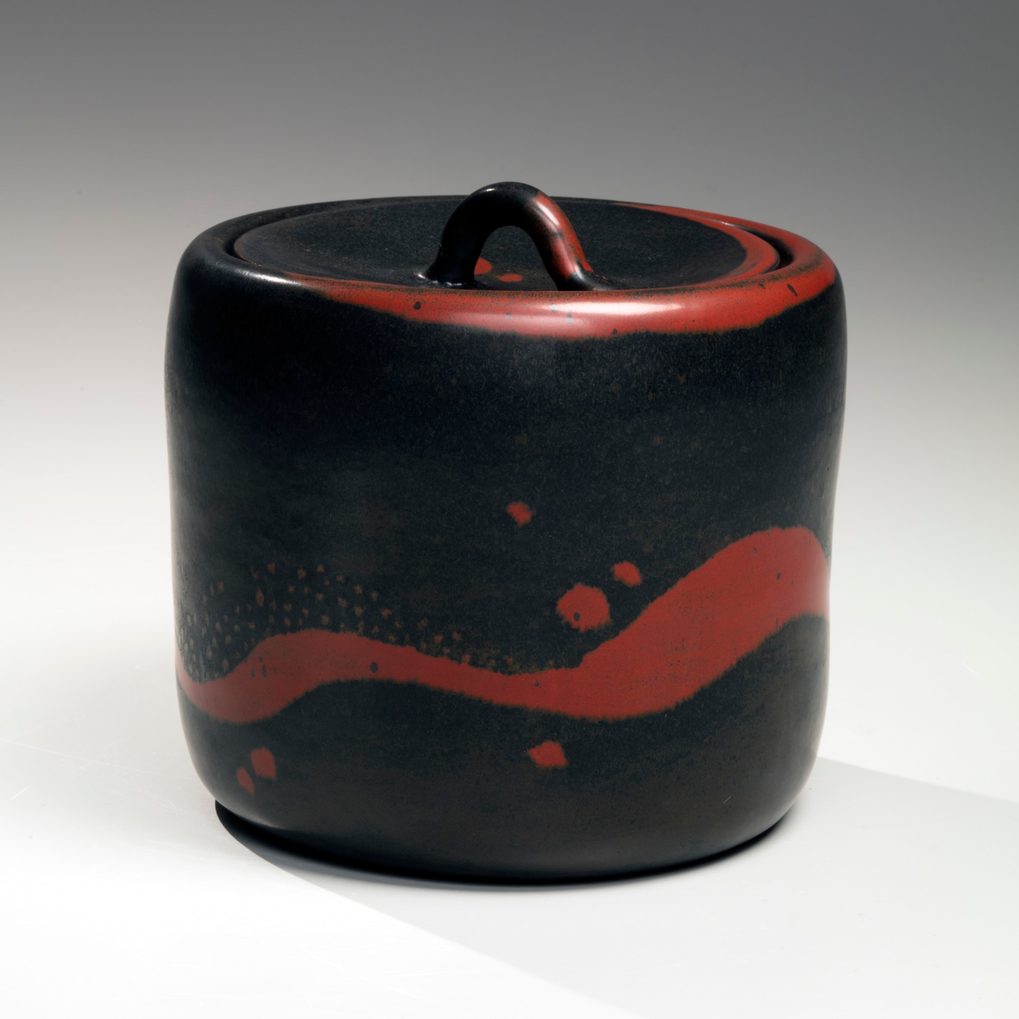 Columnar black-glazed mizusashi (water jar) with red undulating bands and spotted patterning, and recessed matching ceramic lid with looped handle 2016 Glazed stoneware 6 x 6 1/8 in. Inv# 9723