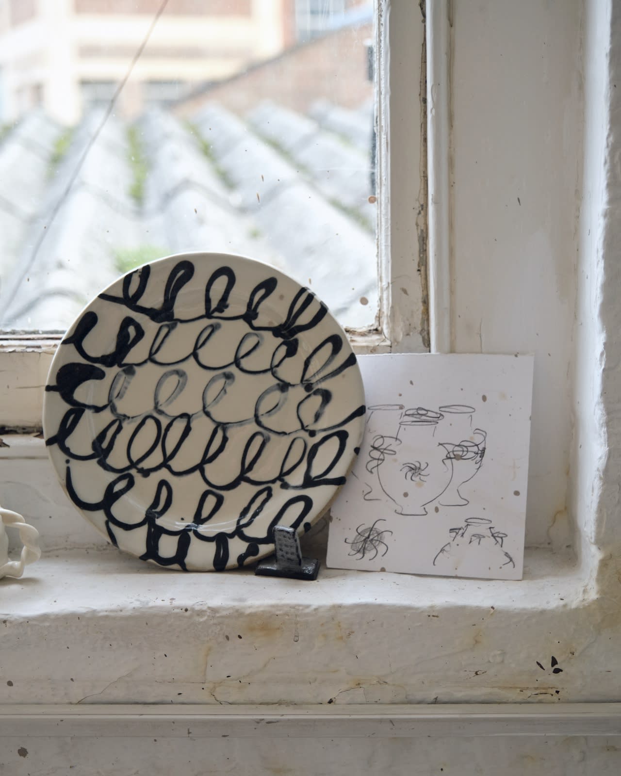 A sliptrailed plate sits slongside drawn designs for caudle cups
