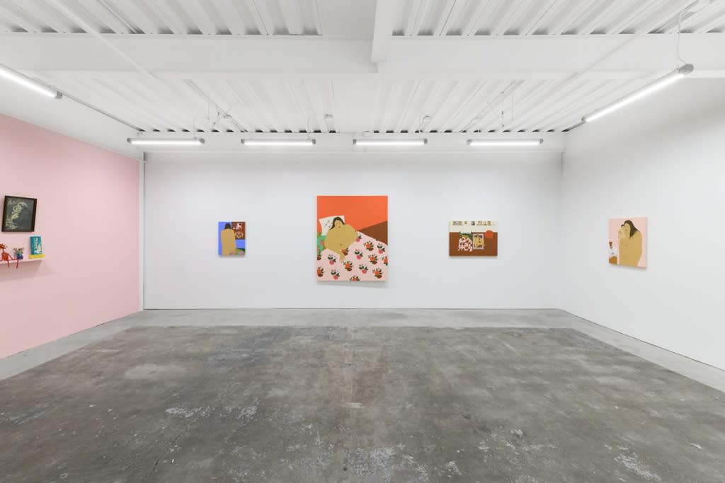 installation of Gina M. Contreras exhibition - pink wall to left with small sculptures and religious paintings, white wall along back and right side. Paintings of nude female figures with patterned floral bedding