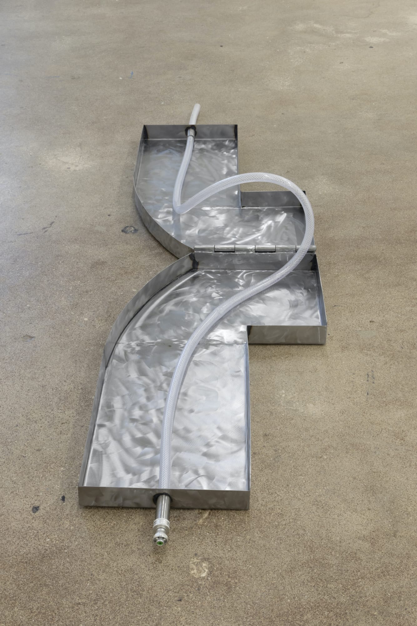 Alina Tenser (b. 1981) Water Carrier, 2023 Sheet metal, hinges, vinyl hose Overall: 2 x 77 x 20 inches; dimensions variable 5.08 x 195.58 x 50.8 cm