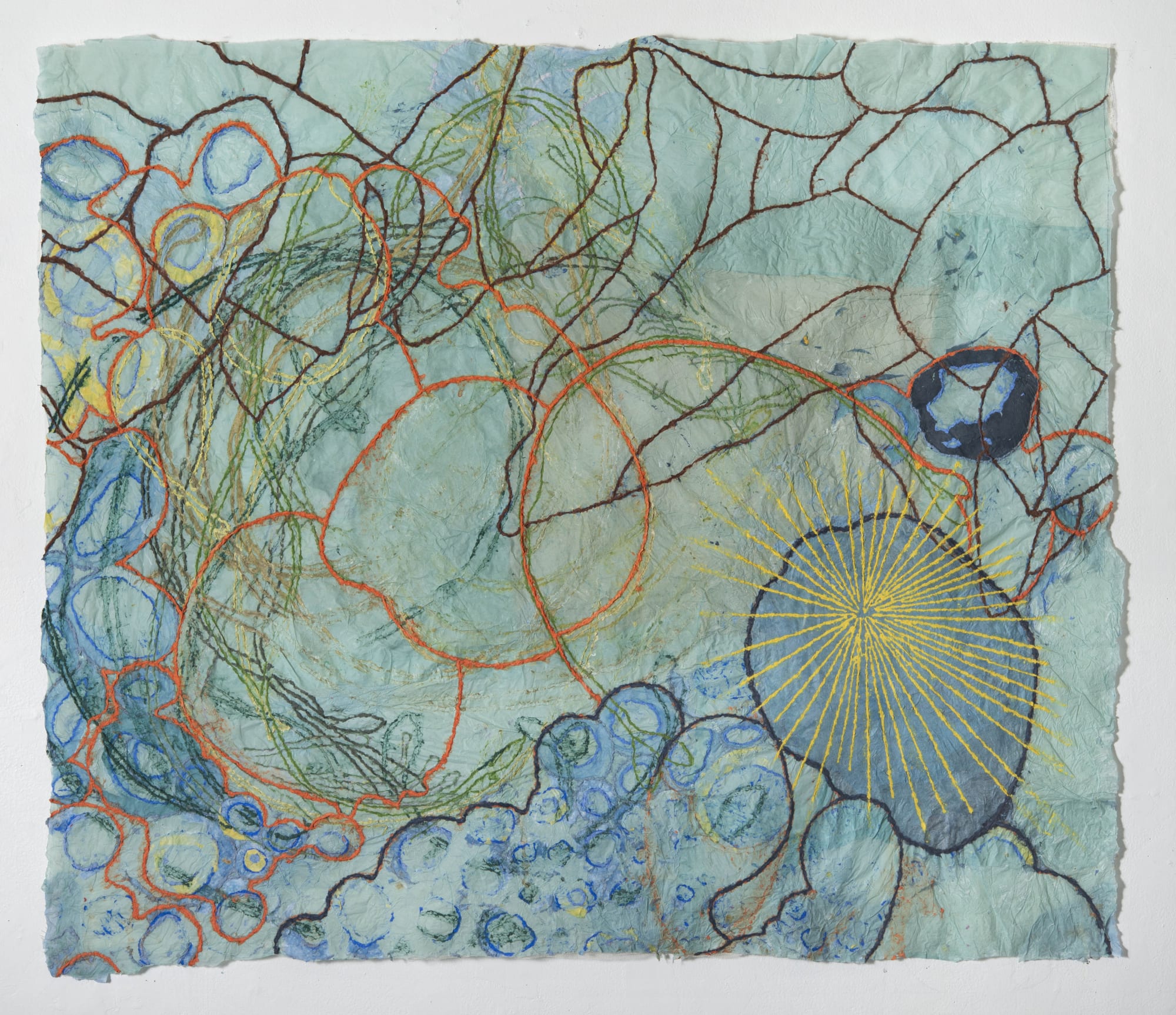 Nancy Cohen's "Dissoulution" done with paper pulp and handmade paper in various shades of green, blue, orange, yellow and brown. The piece depicts several design layers on the light aqua paper. These designs are overlapping each other creating depth.