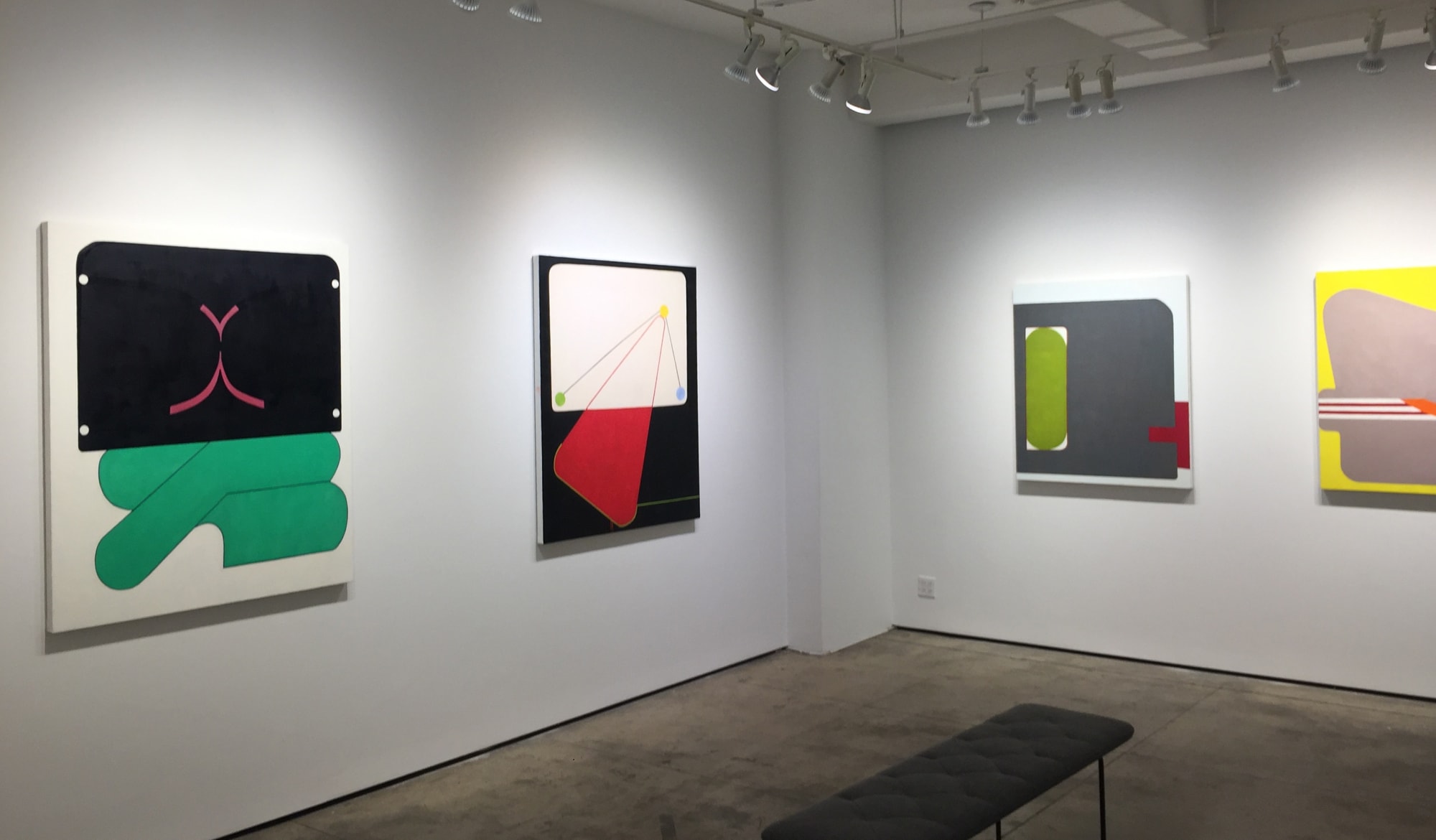 Gallery photograph of an installation featuring four abstract paintings on canvases. 