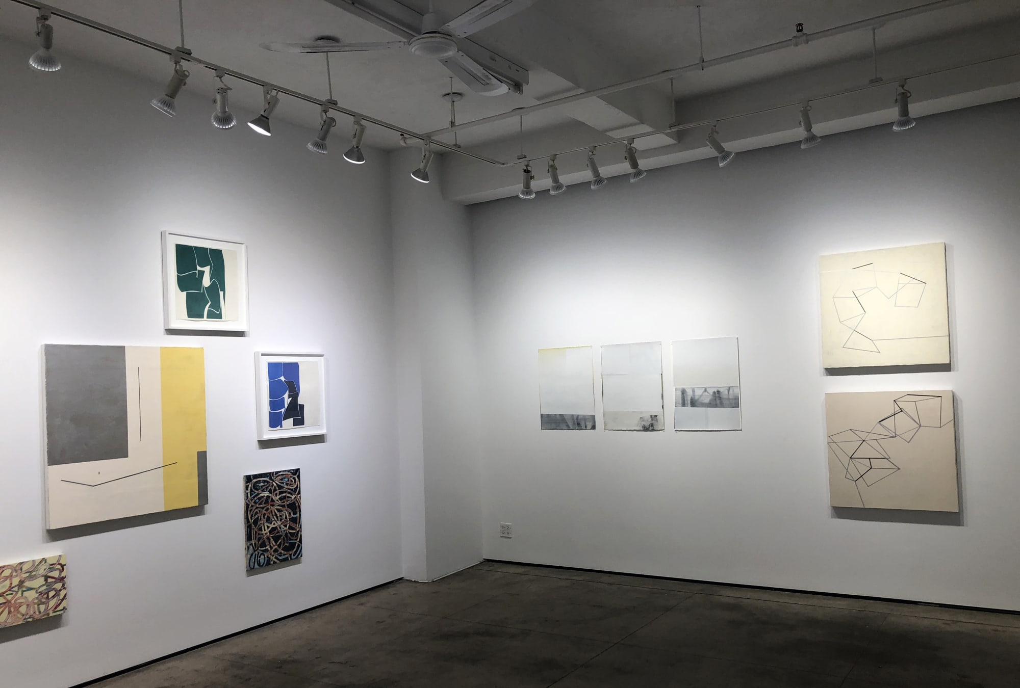 Installation shoot of ten different art pieces. The paintings are in shades of green, blue, yellow, gray and tan.