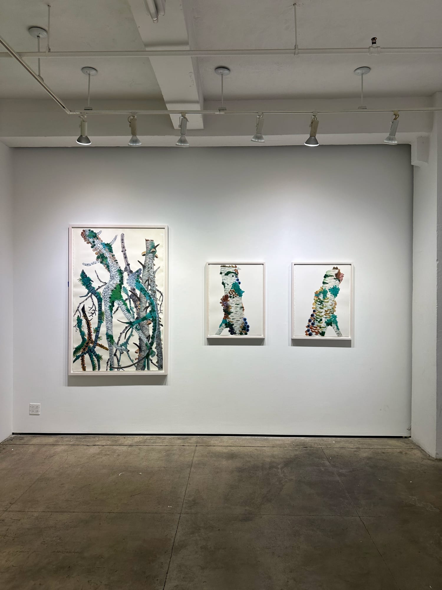 exhibition with three paintings next to each other on the wall