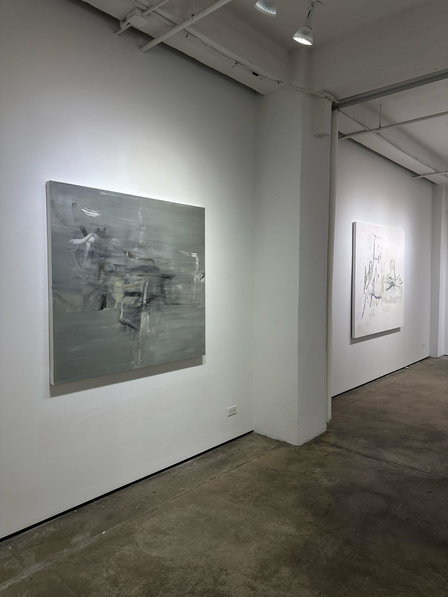 photo of an installation with two large abstract paintings visible.