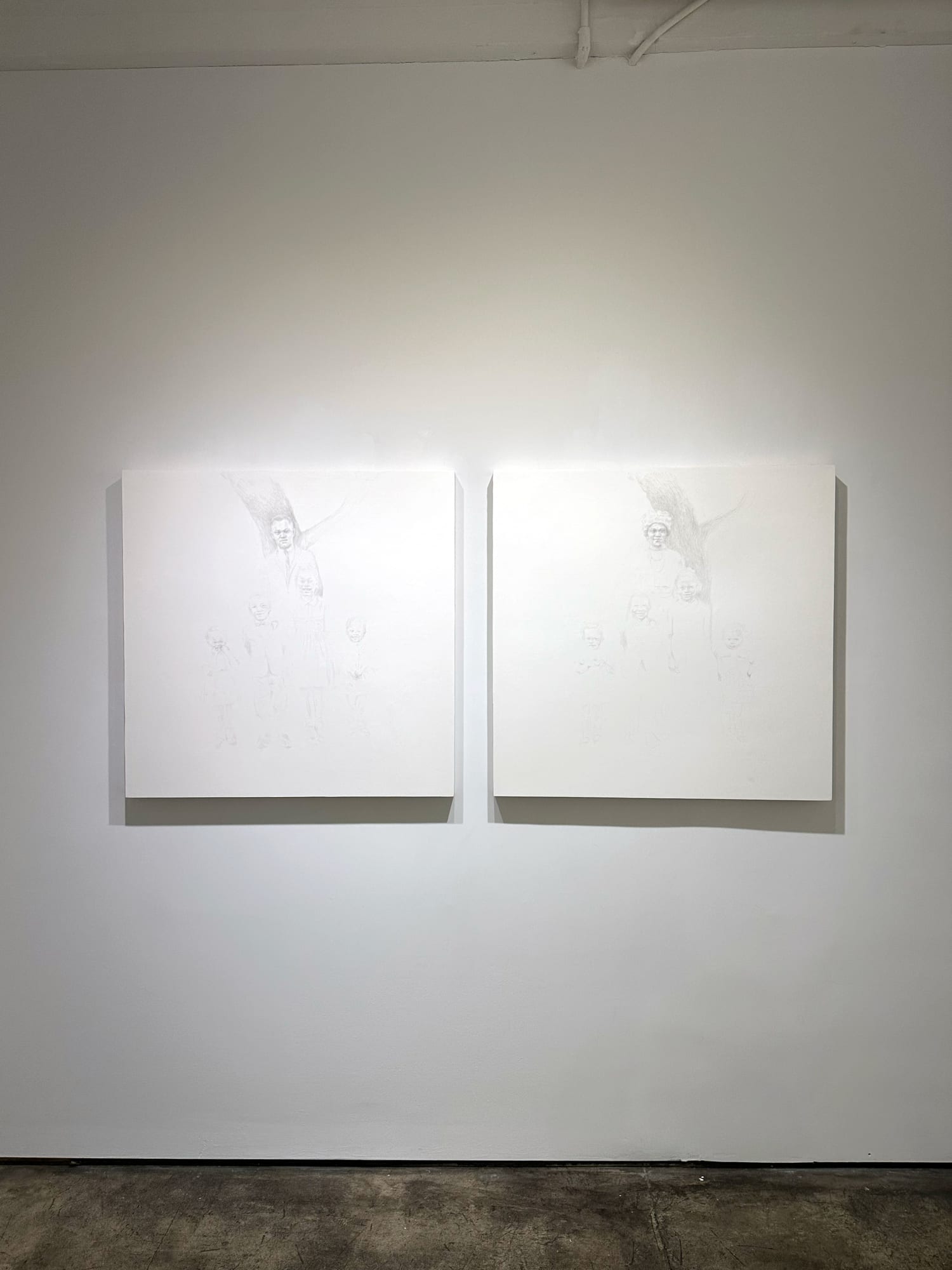 photo of an installation, with two primarily white paintings next to each other on the wall.