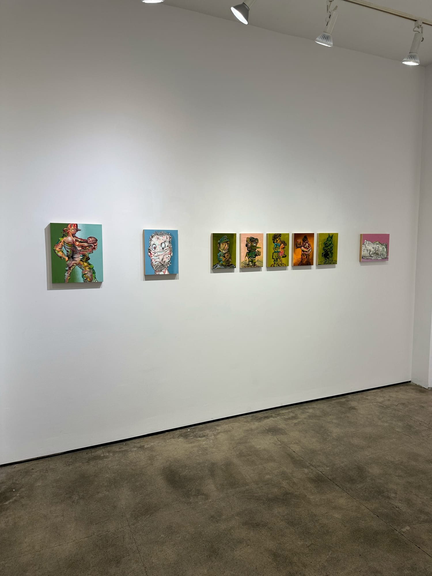 photo of an installation with 8 small paintings placed next to each other on the wall. They are not all the same size, but 5, in the middle, are.
