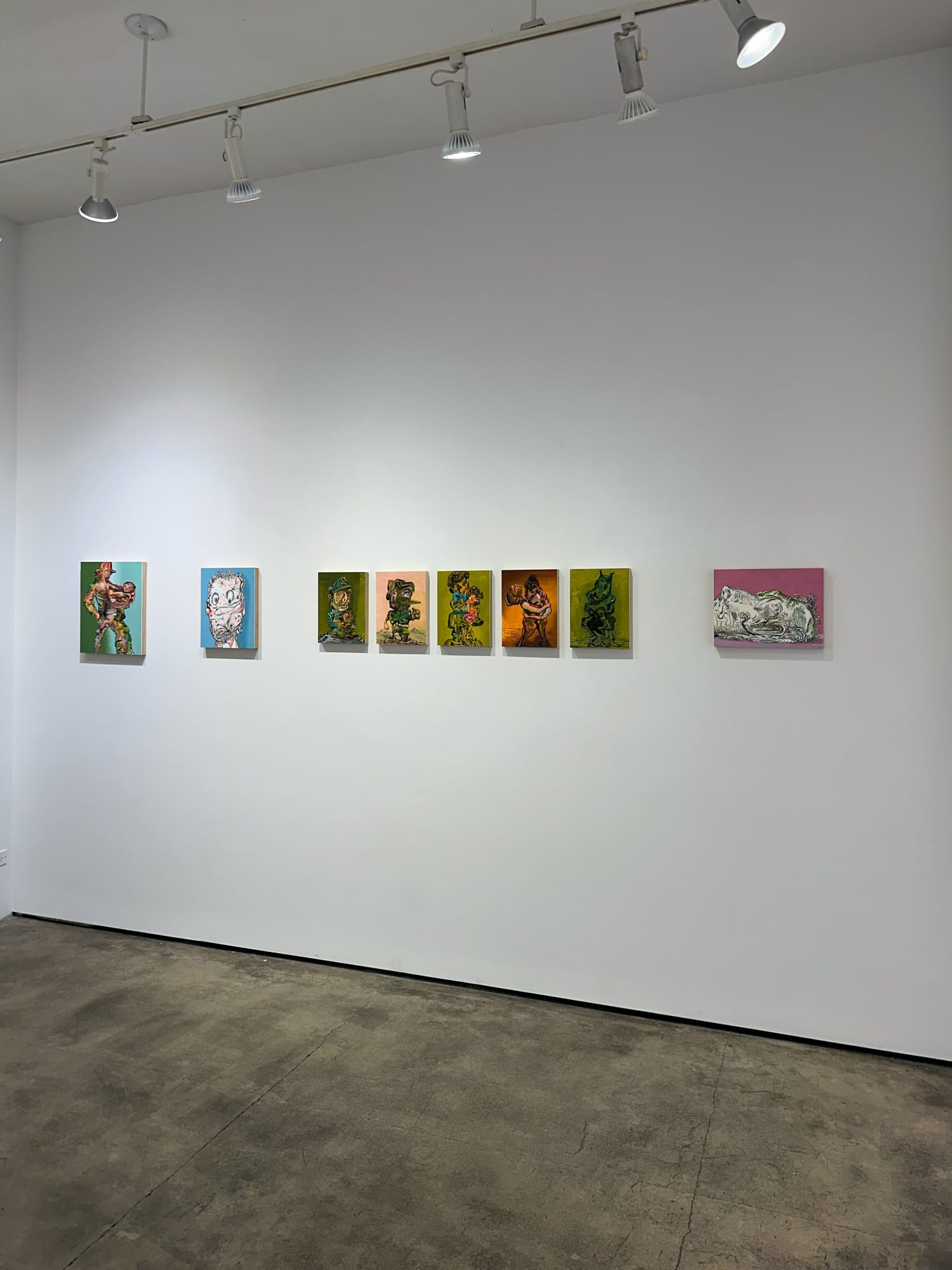 photo of an installation with 8 small paintings placed next to each other on the wall. They are not all the same size, but 5, in the middle, are.