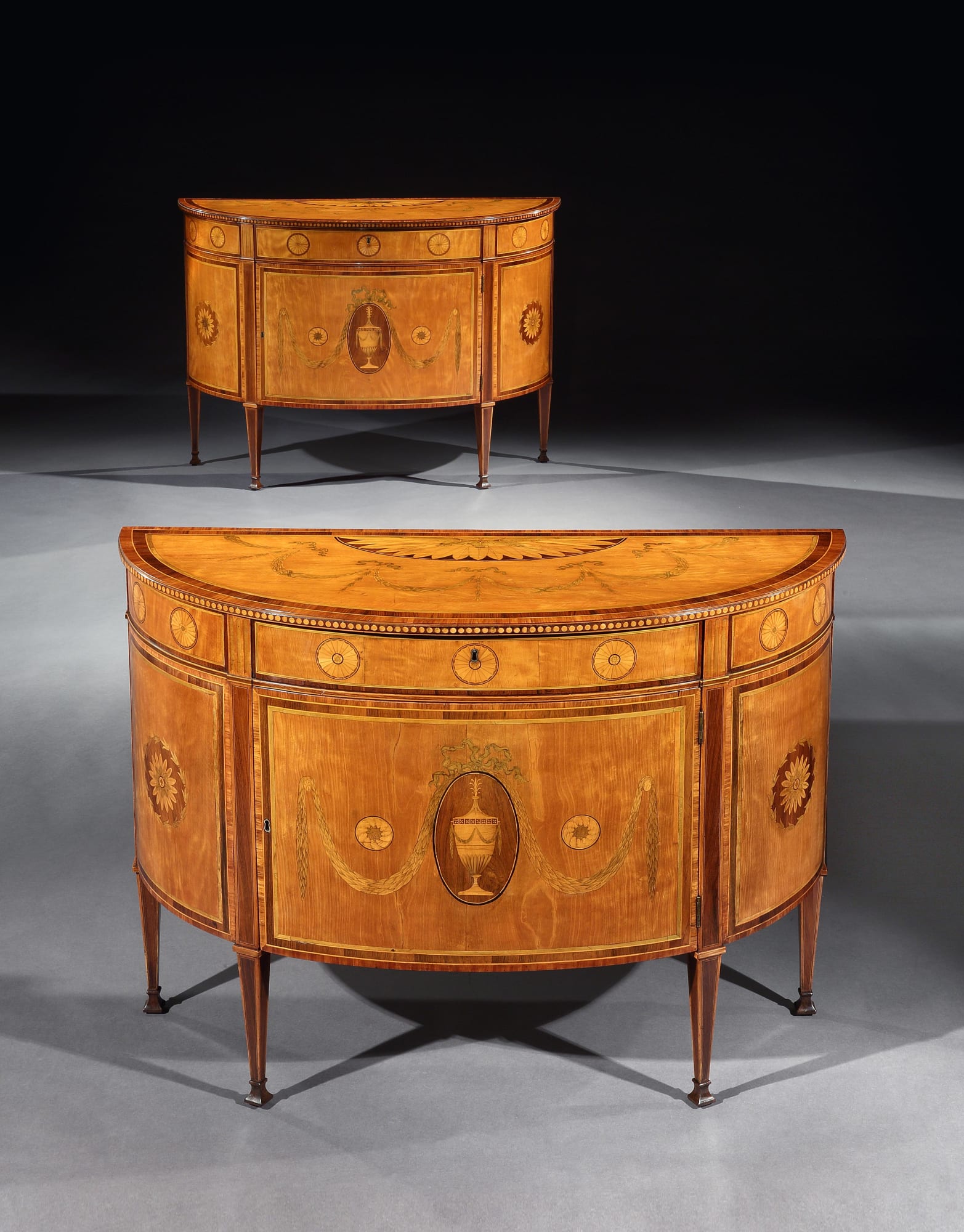 A pair of George III semi-elliptic satinwood commodes by Mayhew & Ince.