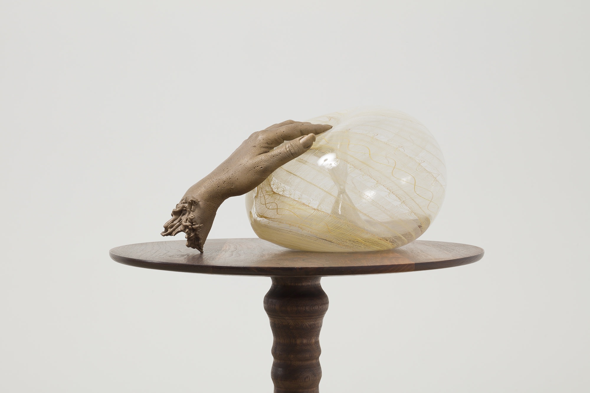 Akashi bronze hand dipping into glass sculpture