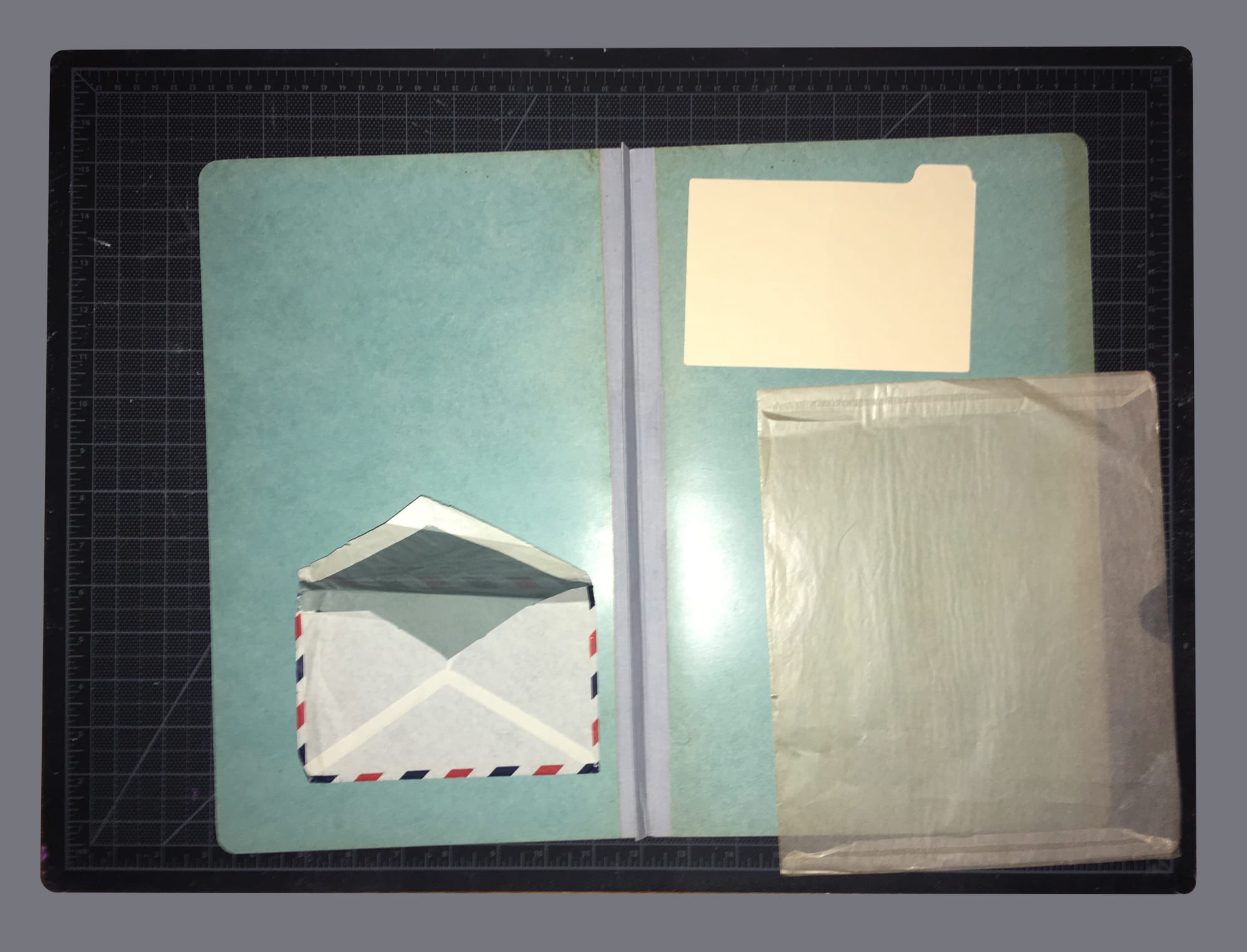 Studio arrangement (2019): cutting mat, glassine folder, manila file divider, envelope