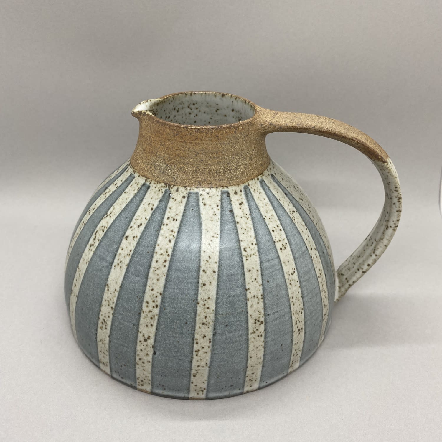 Kate Garwood jug in a squat, round shape, brown at the top with a blue body and white vertical stripes