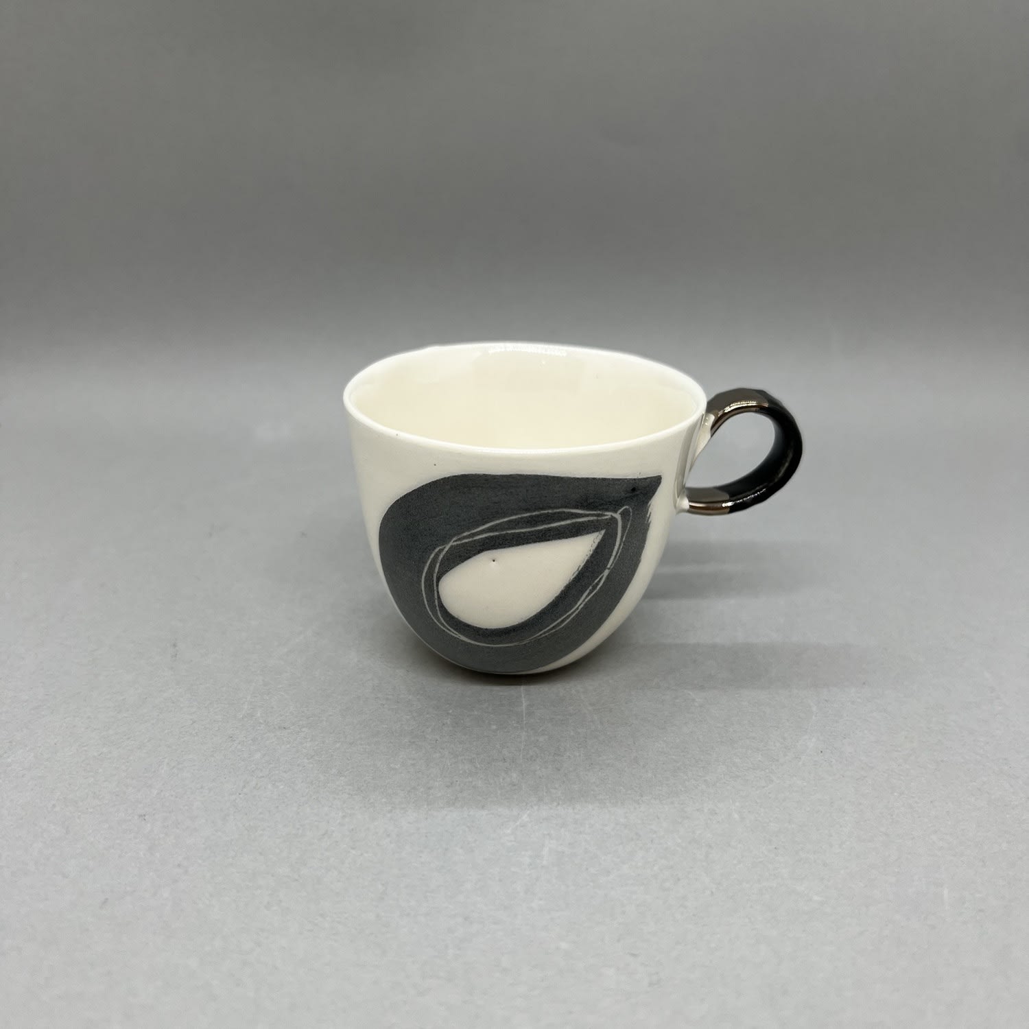 Fliff Carr ceramic espresso cup with painted black droplet pattern and with a black and gold handle.