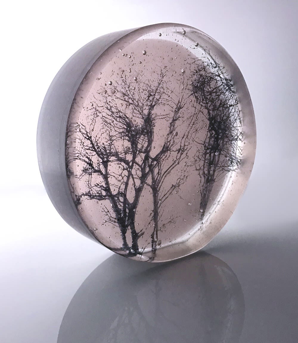 Helen Slater round glass art piece with a silhouette of tree branches against a lilac background which changes colour depending on the light filtering through it.
