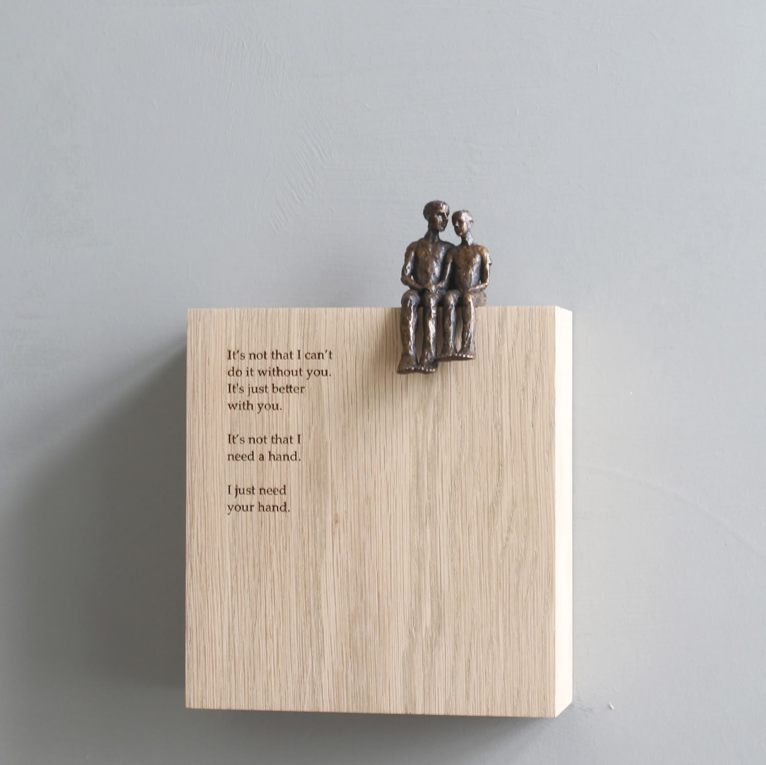Carol Peace small sculpture in bronze of a couple seated on a wooden block, with a text of poetry on the front.