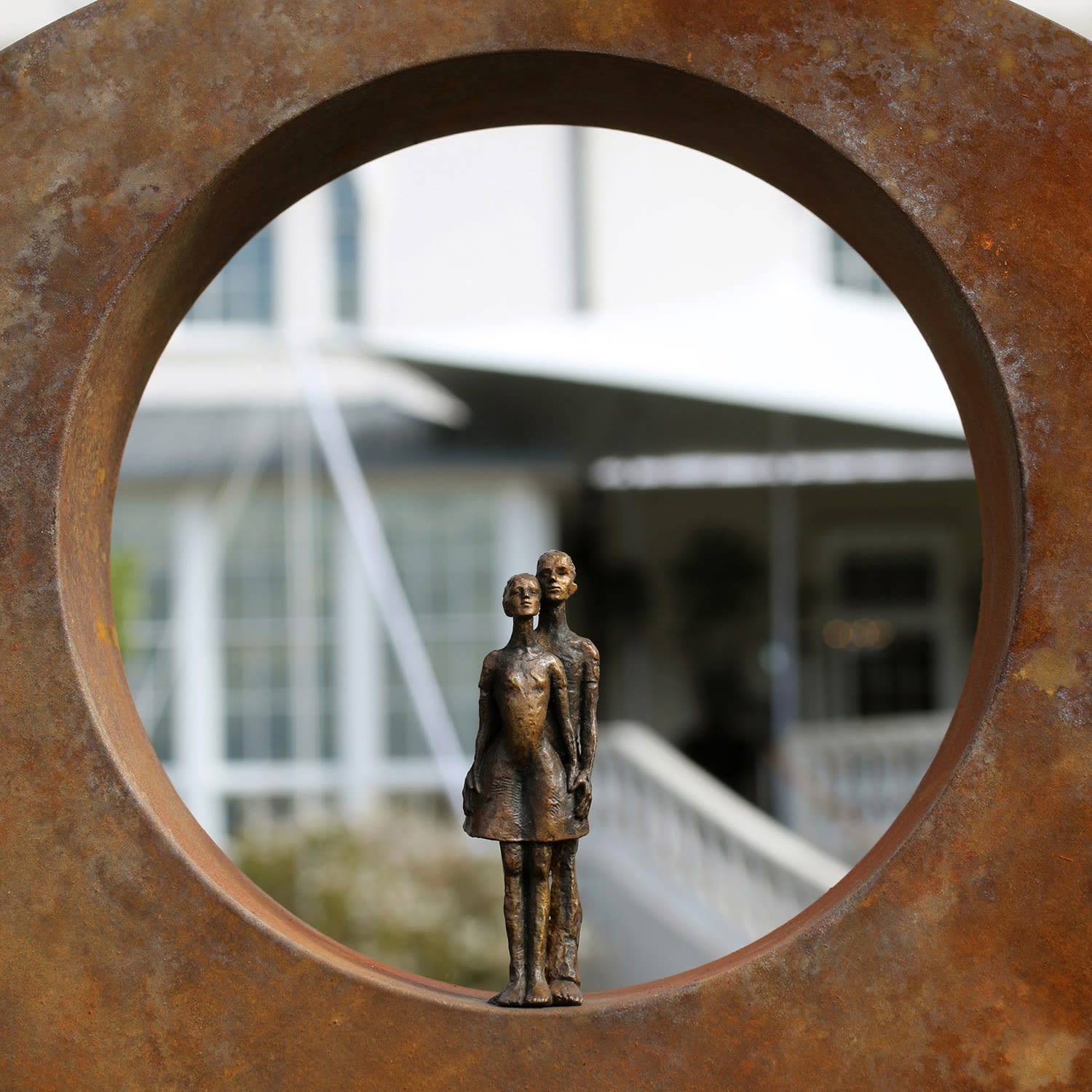 Carol Peace sculpture of small figures of a couple, one standing in front of the other, placed in a thick, wide circle.
