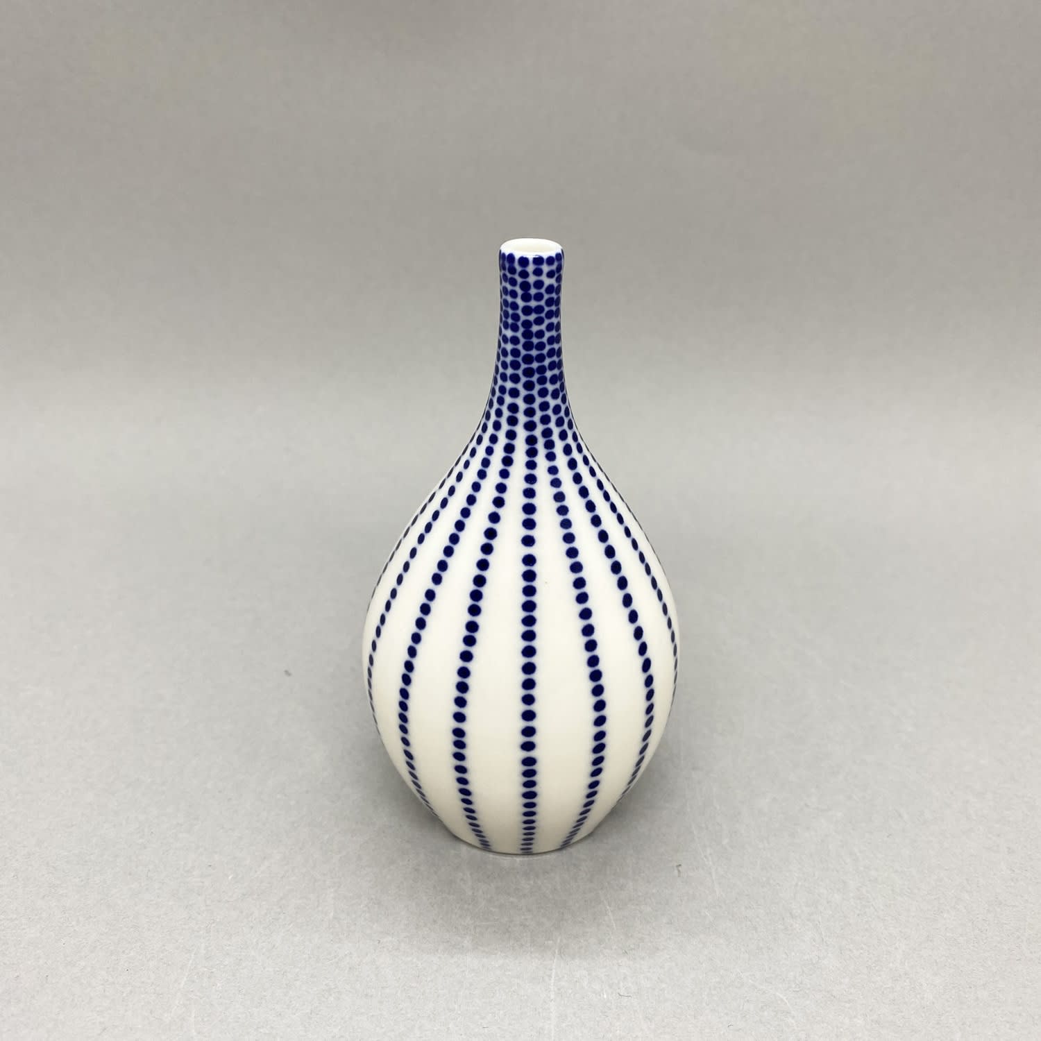 Rhian Malin Small white bottle vase with dotty stripes.