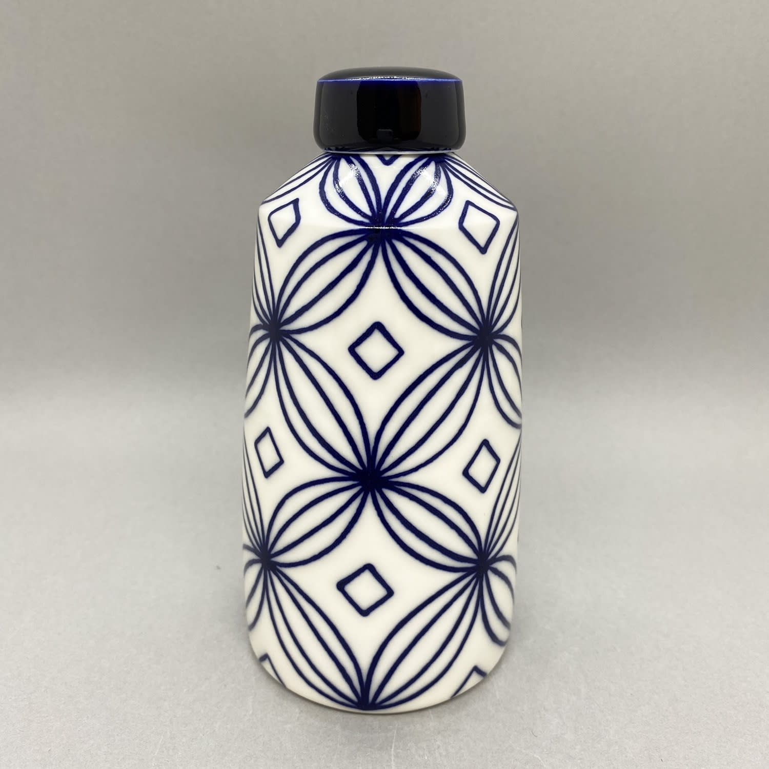 Rhian Malin medium white straight sided ginger jar with flower design in blue with a solid blue lid.
