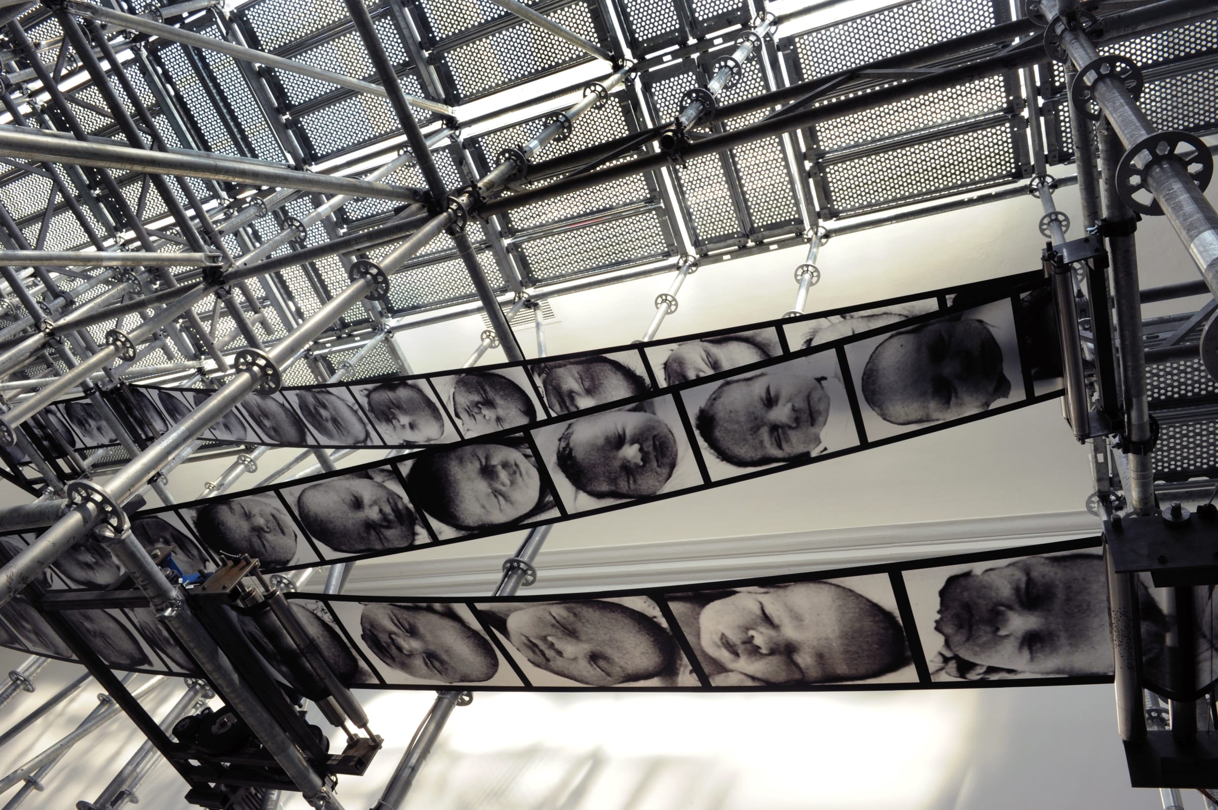A large series of film strips portraying babies hung from a ceiling
