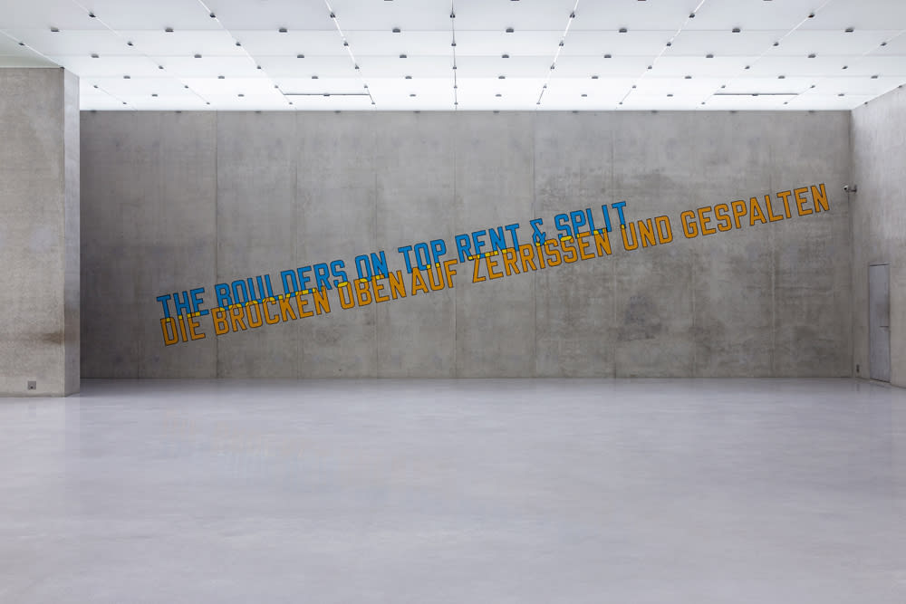 "The boulders on top rent & split" written in English and German on a concrete wall