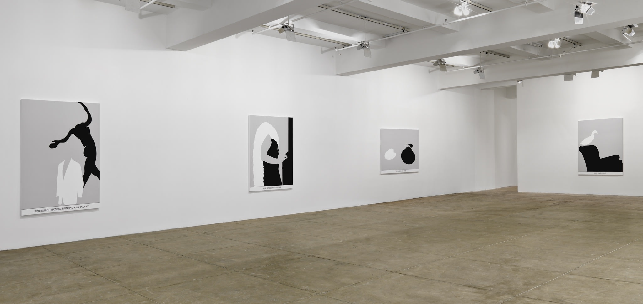 Four black and white paintings hang in a white space with a beige floor.