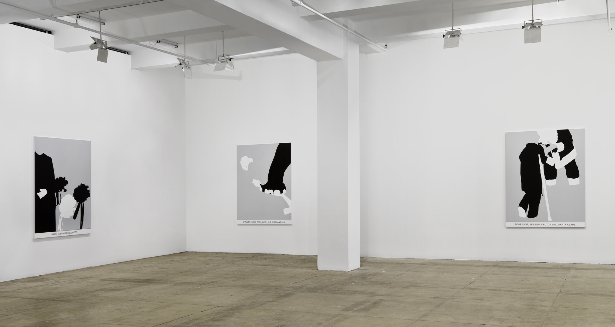 Three black and white paintings hang in a white space with a beige floor.
