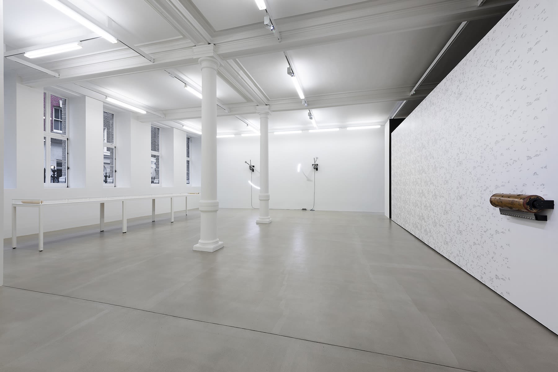 A white gallery room; the wall on the right has a pattern that has been inked on with a roller.