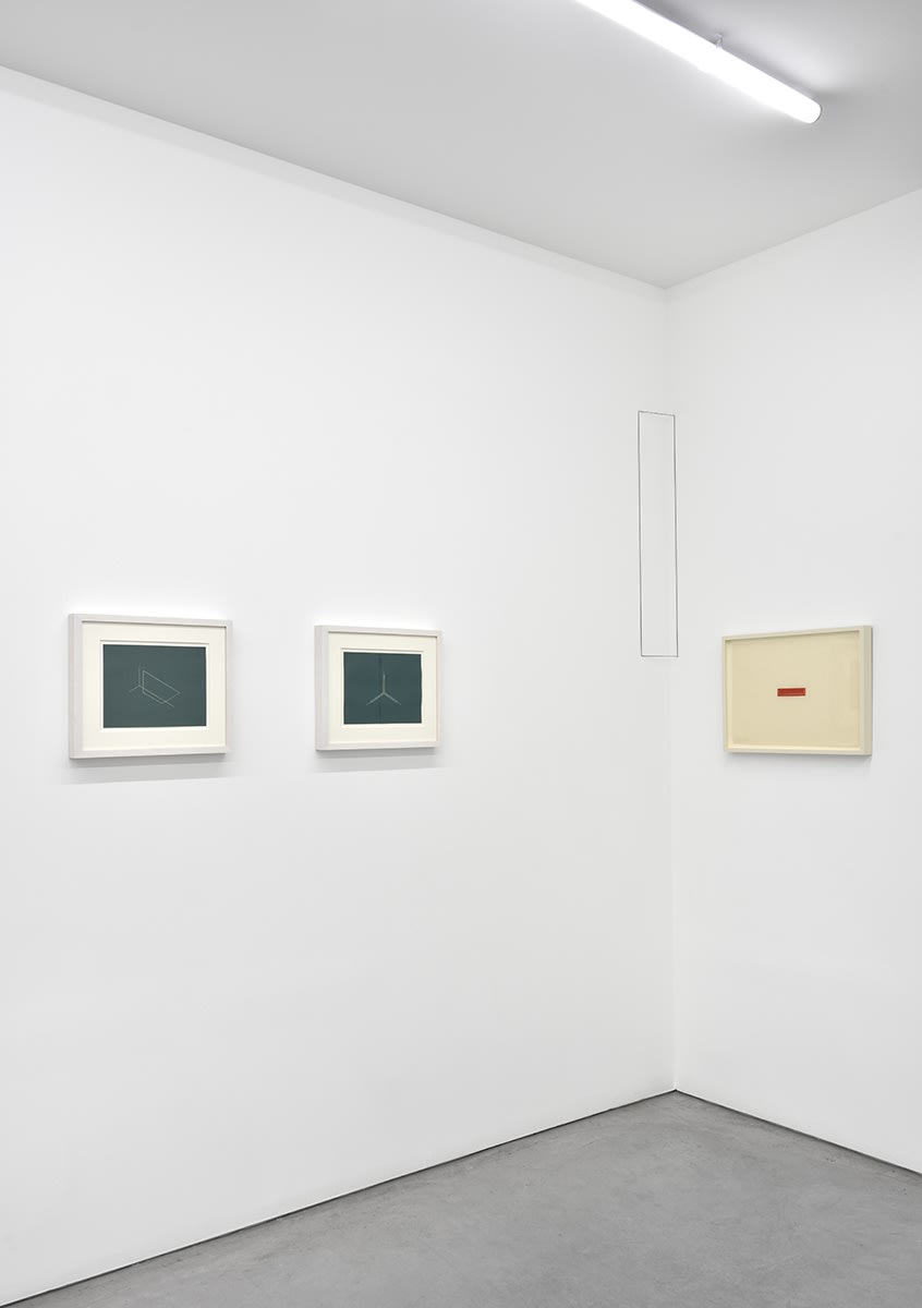 3 small, framed artworks hang in the corner of the gallery.