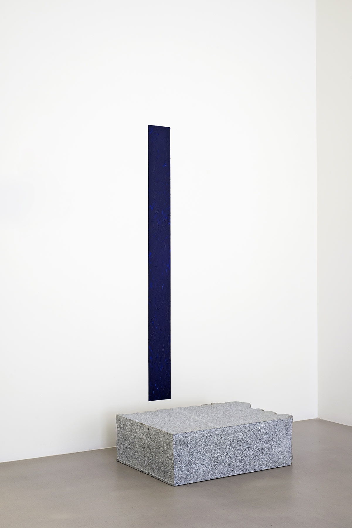 Skinny deep blue painting mounted above slab of granite.