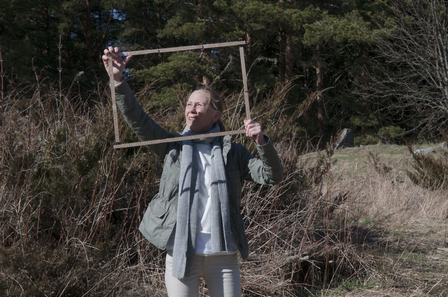 Image of person in field holding a frame made of measuring sticks.