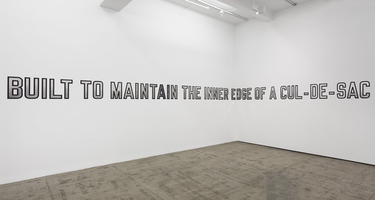 Gallery installation: silver text with black outline reading: BUILT TO MAINTAIN THE INNER EDGE OF A CUL-DE-SAC"