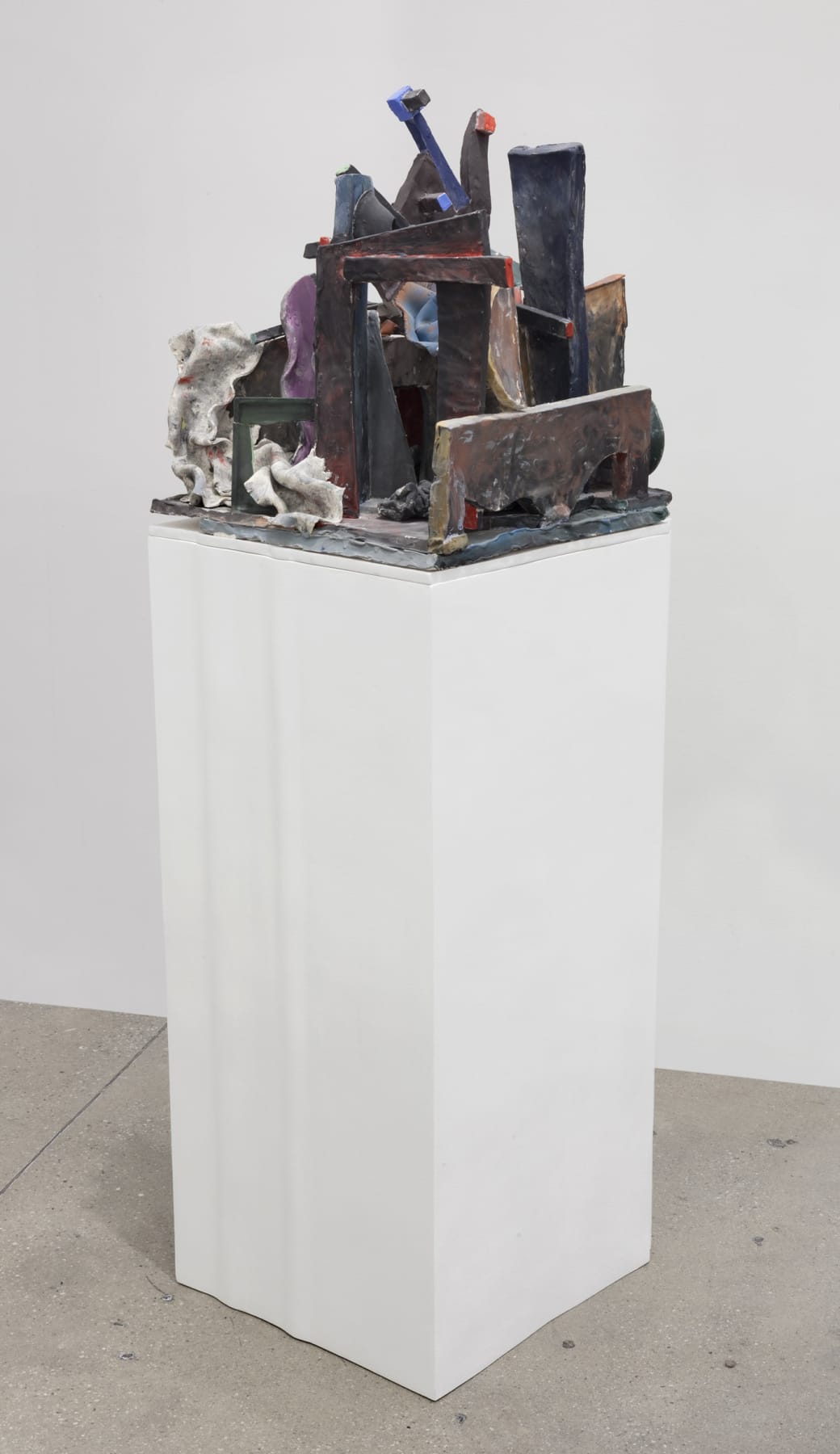An abstract sculpture sits on a white pedestal.
