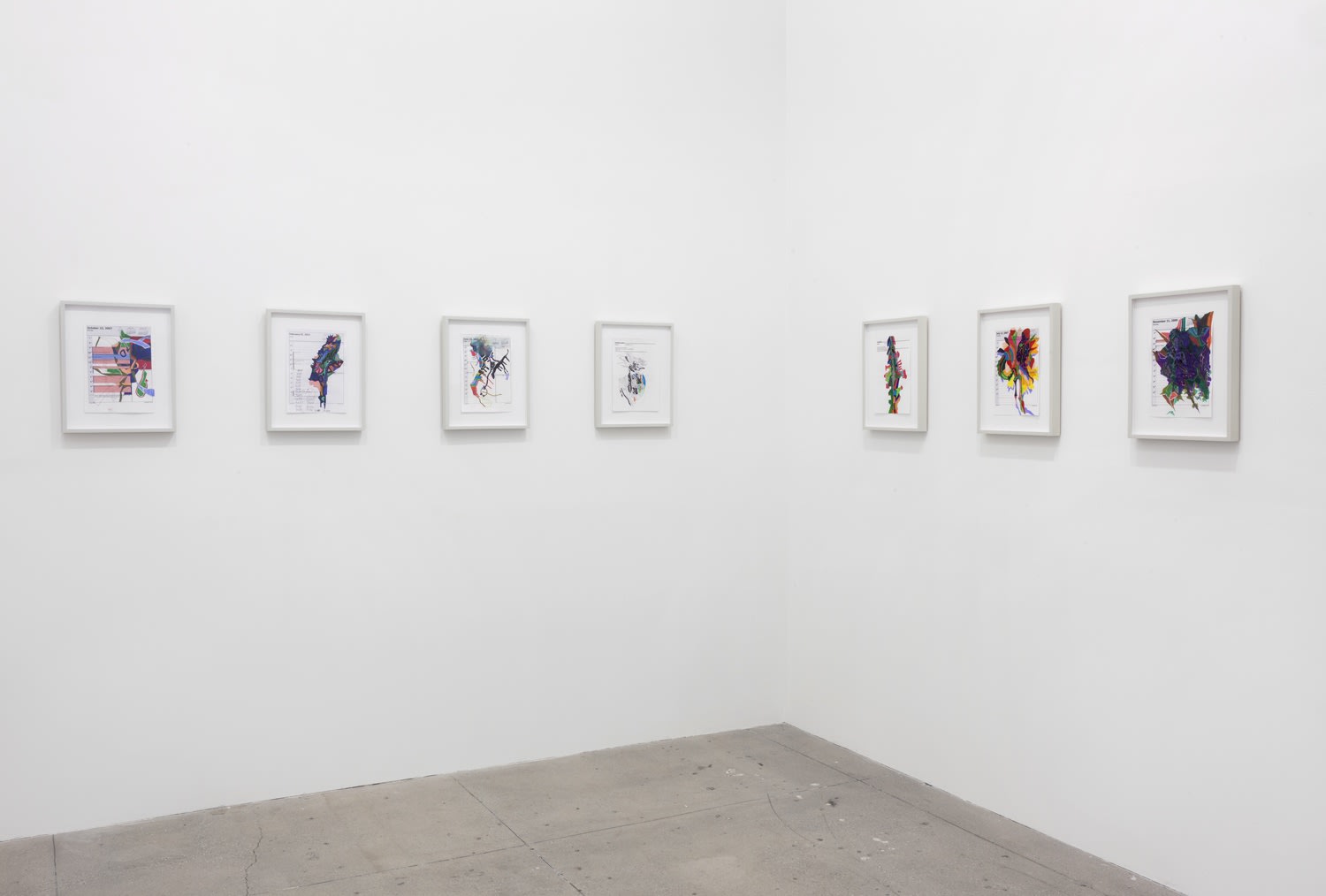 7 small, colorful artworks hang in white frames in a white gallery space.